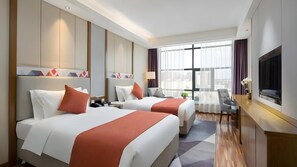Une chambre d’hôtel avec deux lits, un bureau, une télévision et une grande fenêtre avec des rideaux.