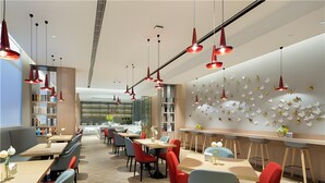 A modern restaurant interior with multiple dining tables, red chairs, and pendant lighting. - Borrman Hotel (Shanghai)