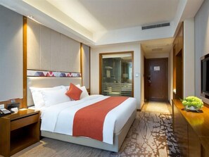 A hotel room with a bed, bedside table, and a television.