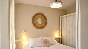 Un dormitorio con cama, un espejo redondo, dos lámparas de noche y una puerta.