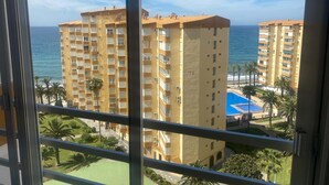 Un edificio alto con balcones, piscina y vista al mar.