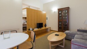 A modern living room with a round table, a sofa, a TV, and a cabinet with glass doors.