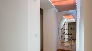 A hallway with a clear archway, a chair, and a neon sign reading 'les grands trans-Parents'.