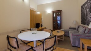 A living room with a round dining table, two chairs, a sofa, a cabinet, and a lamp.