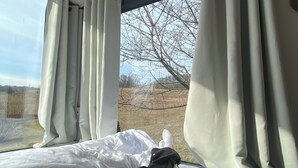 A bed with white bedding and a person lying down. - Tinyhouse in the middle of nature! Perfect for a spontaneous break! (Bad Endbach)