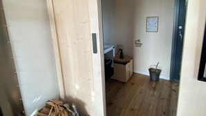 A wooden door with a heart-shaped cutout, leading into a room with a wooden floor, a small table with a spray bottle, and a potted plant. - Tinyhouse in the middle of nature! Perfect for a spontaneous break! (Bad Endbach)