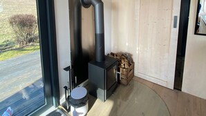 A modern interior with a wood-burning stove, a sliding door, and a view of the outdoors. - Tinyhouse in the middle of nature! Perfect for a spontaneous break! (Bad Endbach)