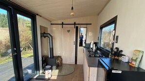 A modern kitchen with a black refrigerator, wooden cabinets, and a large window. - Tinyhouse in the middle of nature! Perfect for a spontaneous break! (Bad Endbach)