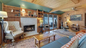 A cozy living room with a fireplace, wooden shelves, a sofa, and a bench. - Updated cabin sleeps 8. Pet friendly, and has private neighborhood beach. (Charlevoix)