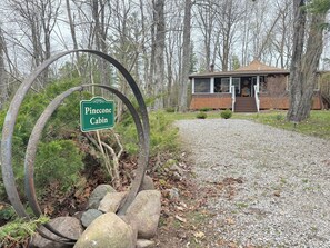 Une cabane appelée « Pinecone Cabin », accessible par un chemin de gravier, et entourée d’arbres.