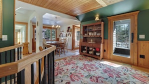 A spacious kitchen with wooden beams, a dining area with a chandelier, and a large window with a view of trees. - Updated cabin sleeps 8. Pet friendly, and has private neighborhood beach. (Charlevoix)