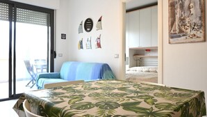 A bedroom with a bed, a chair, a door, and a wall with artwork. - SE140 – Senigallia, two-room apartment on the Mameli seafront (Senigallia)