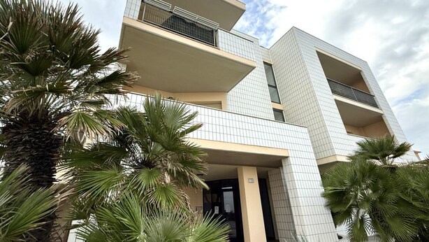 A multi-story building with balconies, palm trees, and a clear sky. - SE140 – Senigallia, two-room apartment on the Mameli seafront (Senigallia)