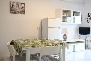 Een kleine kitchenette met een koelkast, een magnetron en een kastje boven het aanrecht.
