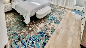 Un dormitorio moderno con una cama grande, una mesita de noche, una lámpara de pie y una ventana con cortinas.