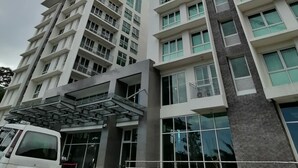 A modern hotel with multiple floors, a prominent entrance, and a visible construction crane in the background. - Condo 604, w/ Pool & Gym & Minutes to Baguio city Attractions (2600 Baguio City)