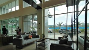 A spacious lobby with large windows, a sofa, a coffee table, and a reception desk. - Condo 604, w/ Pool & Gym & Minutes to Baguio city Attractions (2600 Baguio City)