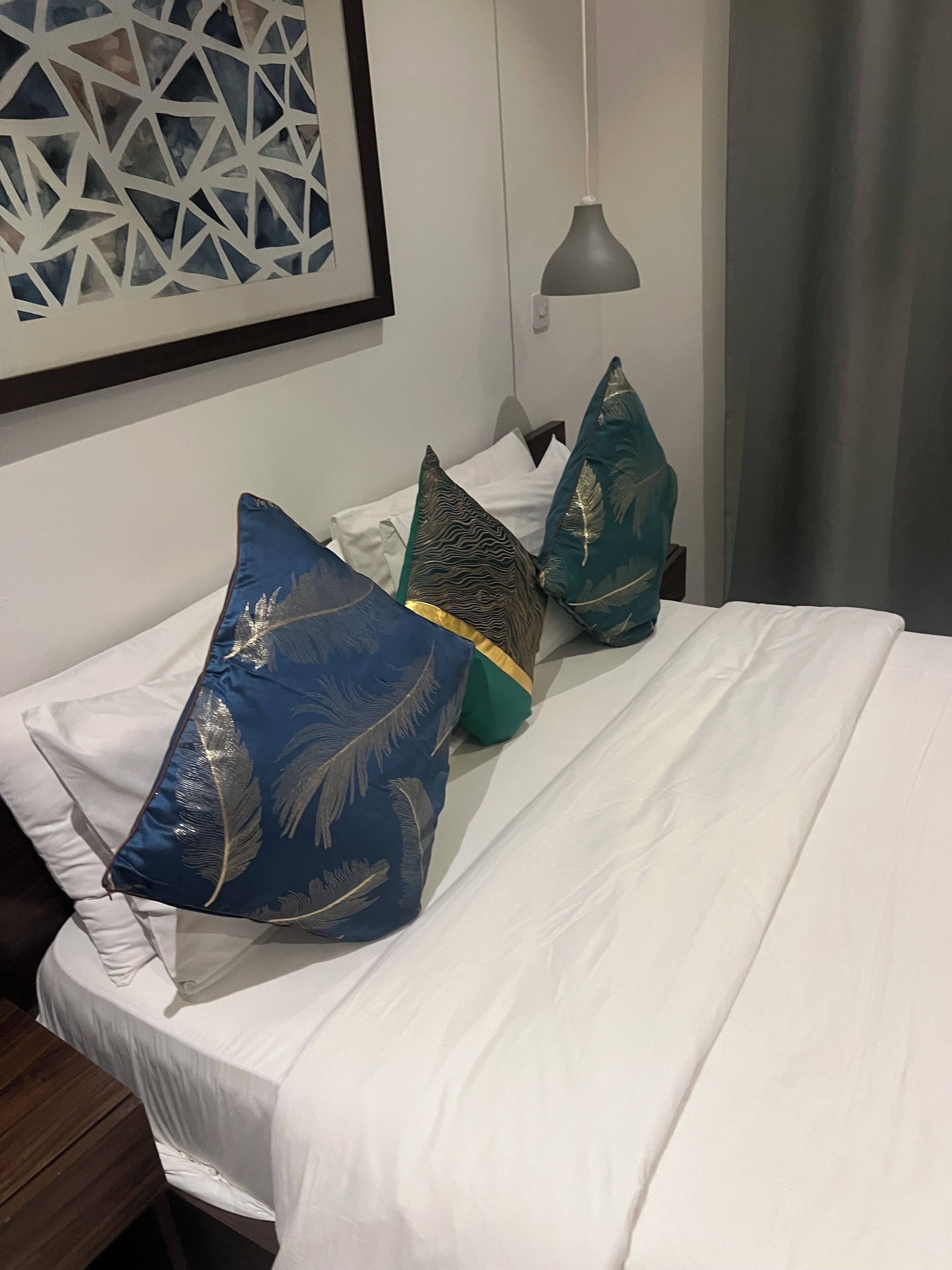 Una cama bien tendida con sábanas blancas y almohadas decorativas en una habitación de hotel.