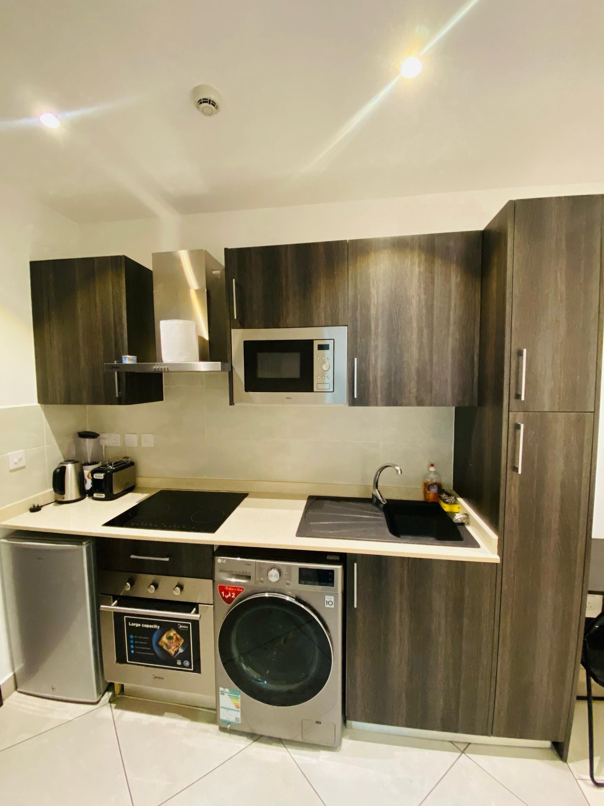 A compact kitchen with a microwave, toaster, sink, and built-in oven.