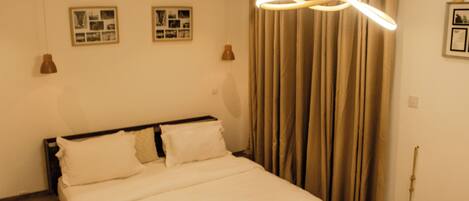 A bedroom with a bed, curtains, and two wall-mounted picture frames.