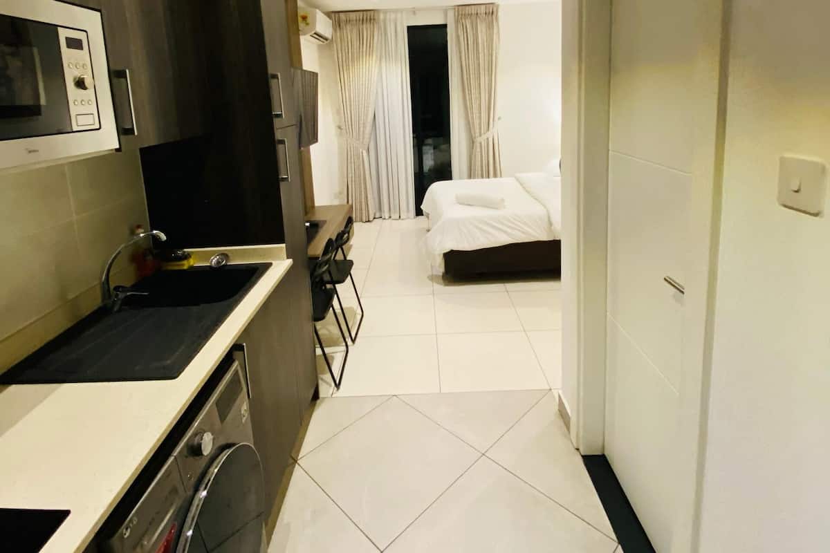 A compact hotel room with a kitchenette, a bed, and a bathroom.