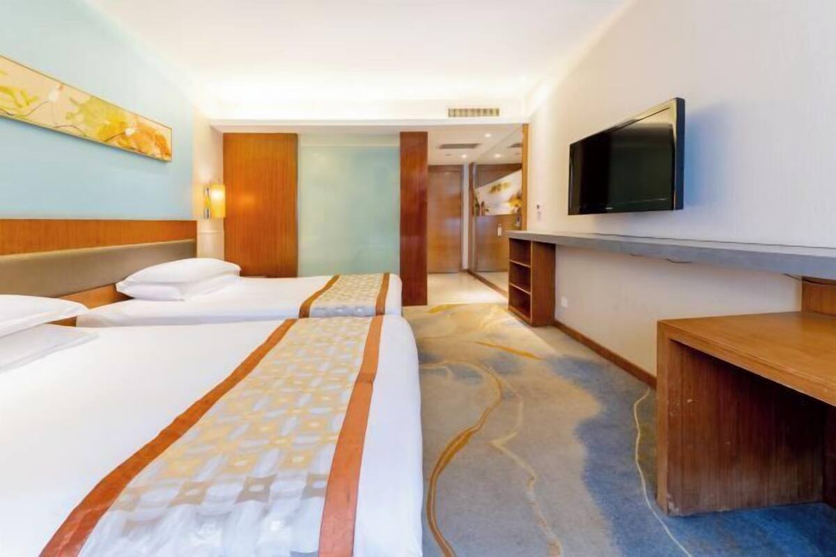 Une chambre d’hôtel avec deux lits, une télévision et un bureau.
