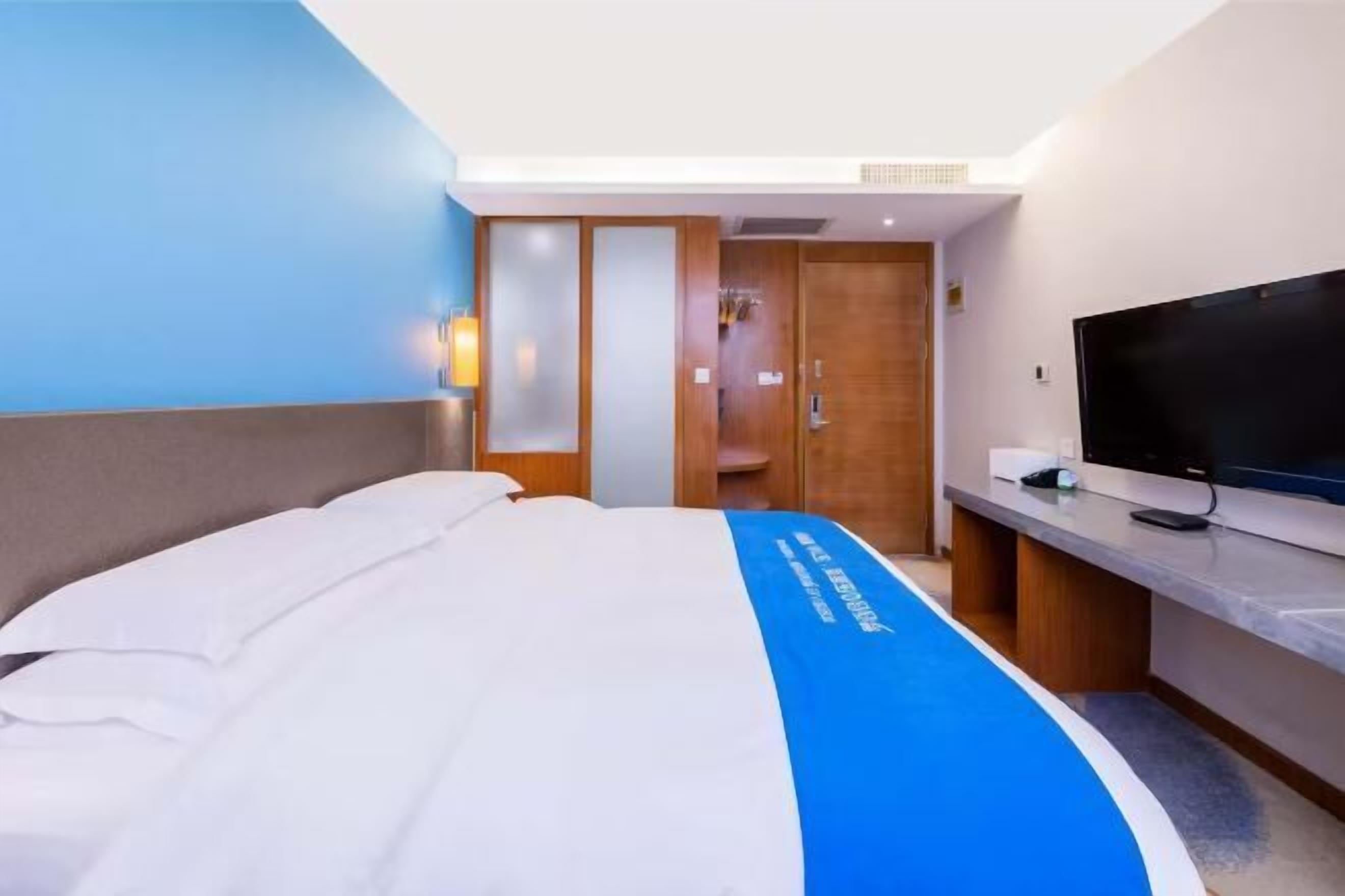 A hotel room with a bed, a TV, a desk, and a wardrobe.