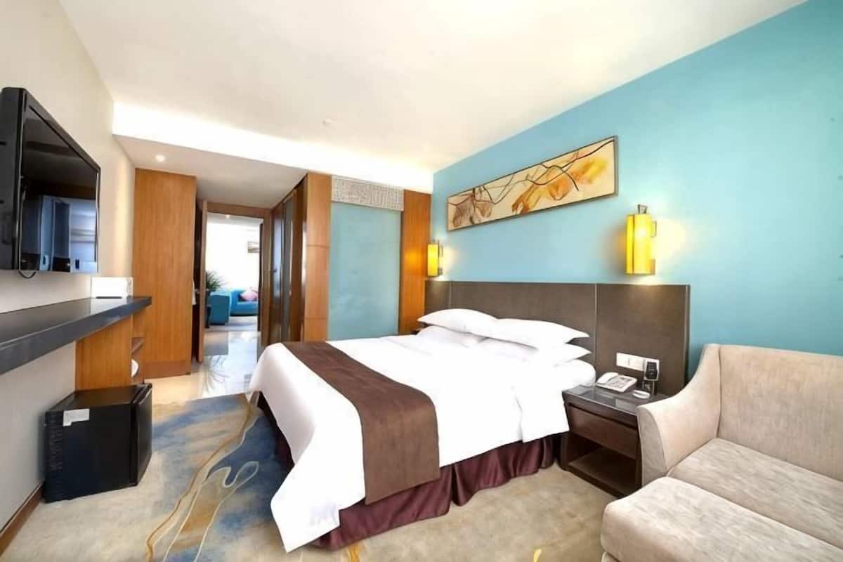 Une chambre d’hôtel avec un lit, une télévision, un bureau, une chaise et un tableau au mur.