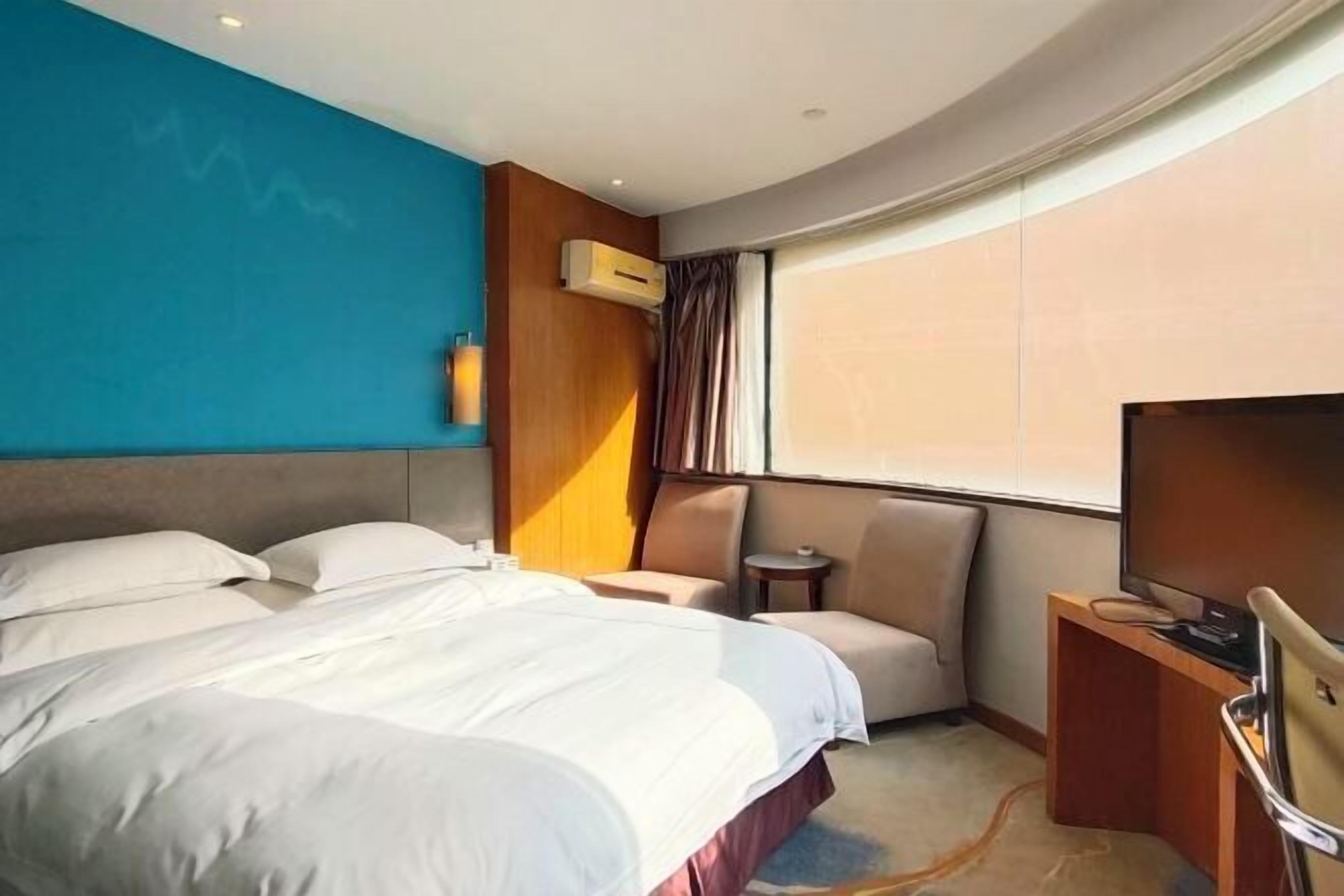 Een hotelkamer met een groot bed, een televisie, een klein tafeltje en een stoel.