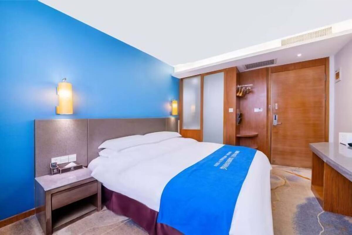 Une chambre d’hôtel avec un lit, une table de chevet et une armoire en bois.