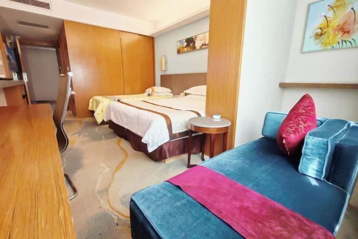 Une chambre d’hôtel avec un lit, un canapé, une petite table et un tableau au mur.
