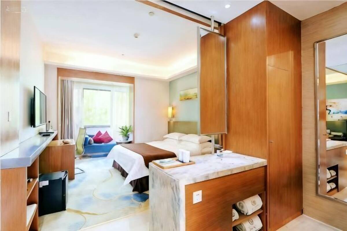 Une chambre d’hôtel équipée d’un lit, d’un bureau, d’une télévision, d’une salle de bain et offrant une vue sur l’extérieur.