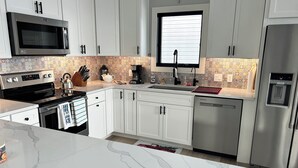 Une cuisine moderne avec des armoires blanches, des appareils en acier inoxydable et un pare-feu décoratif.