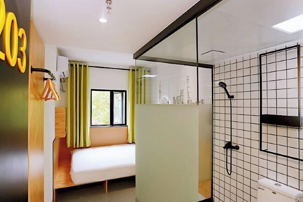A modern hotel room with a bed, a shower, and a window with curtains.