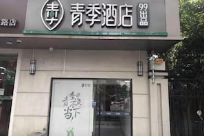 A hotel entrance with a signboard displaying the name and a large poster with text. - Changee Hotel (Shanghai Baoshan Wanda Gongkang Road Subway Station) (Shanghai)