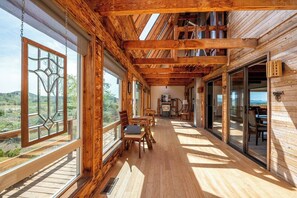 Une cabane en bois dotée d’un balcon, de grandes fenêtres et d’un coin repas.