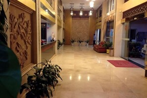 A hotel lobby with a marble floor, a reception desk, and potted plants. - Jinmei Hotel (Jiaoling)
