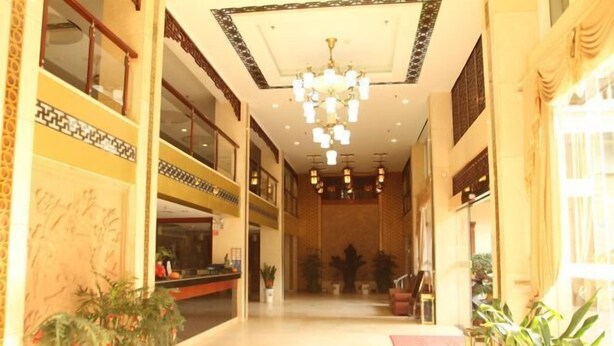 A spacious lobby with a high ceiling, chandeliers, and potted plants.