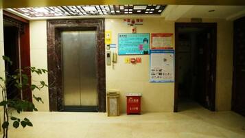 An elevator area with a door, a wall-mounted emergency phone, and informational posters.