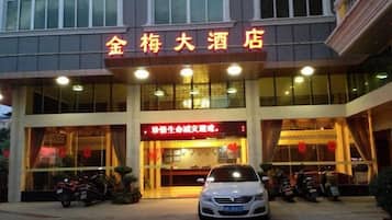 A hotel entrance with a signboard, a car, and motorcycles parked in front.