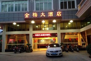 A hotel entrance with a signboard, a car, and motorcycles parked in front. - Jinmei Hotel (Jiaoling)