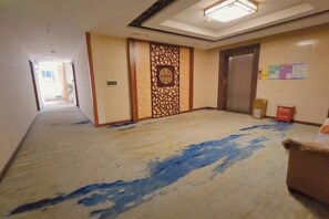 A hotel corridor with a carpeted floor, a decorative wall panel, and a door. - Jinmei Hotel (Jiaoling)