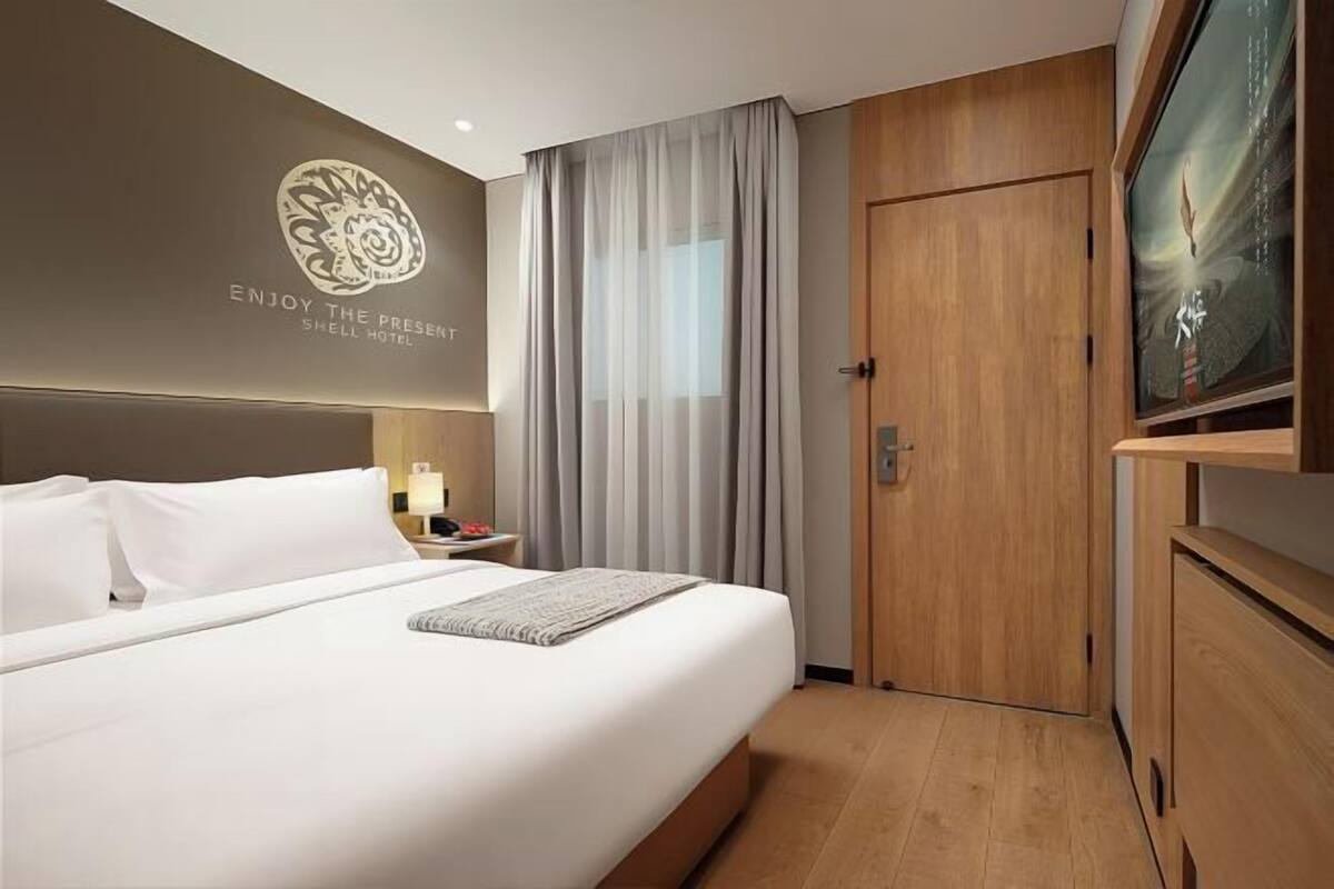 Ein Hotelzimmer mit einem Bett, einem Fernseher, einer Tür und einer Wand mit einem Logo.