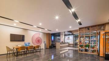 A modern lobby with a reception desk, seating area, and a display of products.
