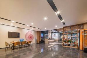 A modern lobby with a reception desk, seating area, and a display of products. - Shell Hotel (Shunyi Ideal Automobile Base, Beijing) (Beijing)