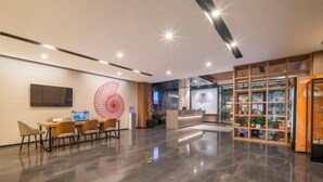 Eine moderne Lobby mit Empfangstresen, einer Sitzecke mit Stühlen, einem großen dekorativen Ventilator und einer Ausstellung auf Regalen.