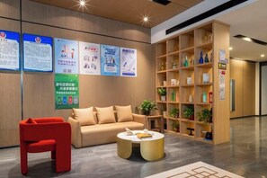 A lobby with a sofa, red chair, coffee table, and a bookshelf. - Shell Hotel (Shunyi Ideal Automobile Base, Beijing) (Beijing)