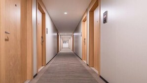 Ein langer, schmaler Hotelkorridor mit Holztüren an beiden Seiten und Teppichboden.