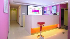 A reception area with a digital screen displaying information, a red bar stool, and a hallway leading to another room. - 100 Inn (Shanghai Jiangpu Road Metro Station) (Shanghai)