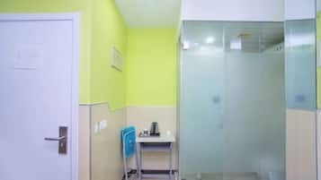 Un baño con ducha, lavamanos y una silla.